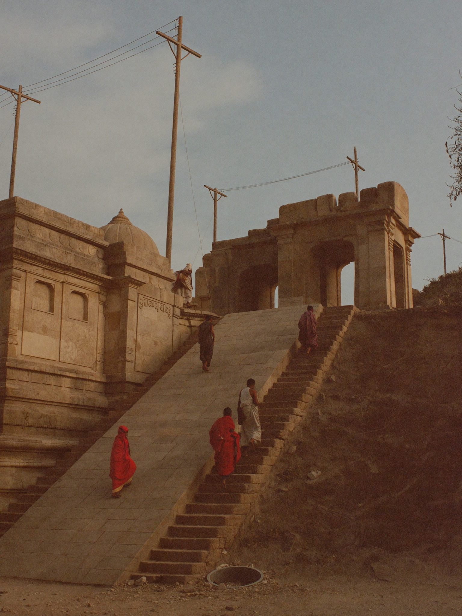 पुराने मंदिर की घिसी सीढ़ियों पर बैठे श्रद्धालु